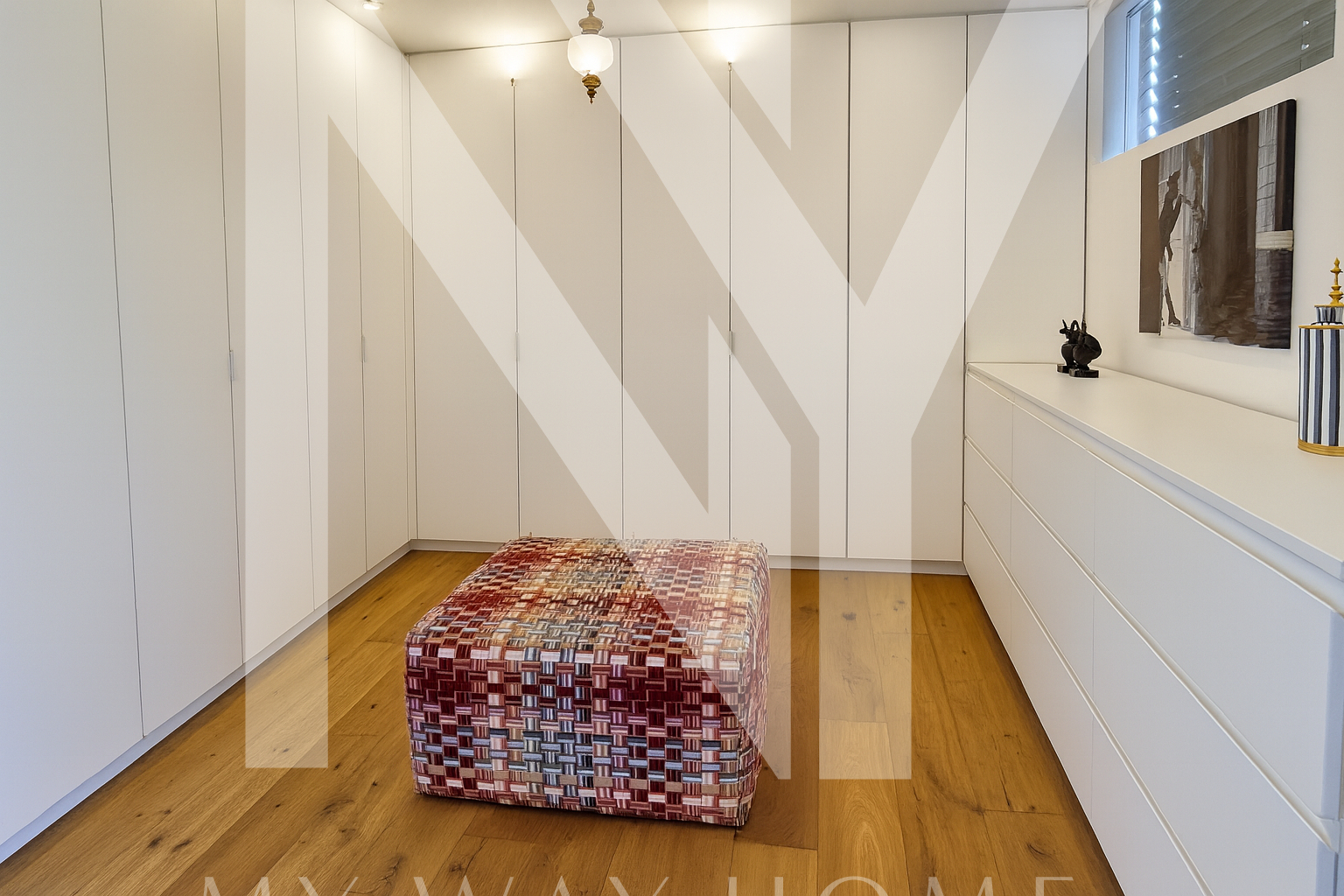 Modern walk-in closet with white cabinets and wooden floor in Ra’anana luxury villa